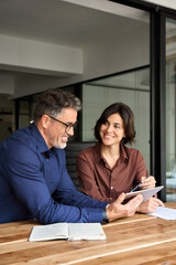 Vertical photo of busy happy professional business people, two business man and woman executives partners team working together in office using digital tablet talking on company financial project.