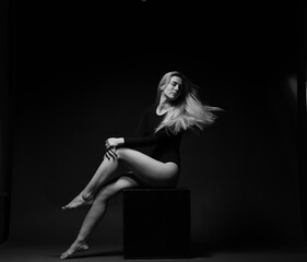 emotional portrait of a beautiful woman with blond hair on a dark background in full growth black and white photo