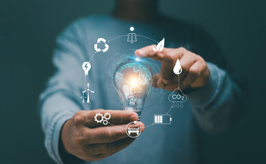 Creative ideas of saving energy and renewable power concept, Hand holding light bulb with icons energy sources for renewable, Alternative energy. Ideas for energy management. Sustainable development.