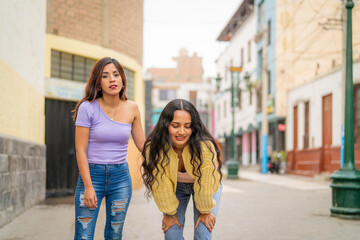 Woman helping her friend who feels sick while walking in the city