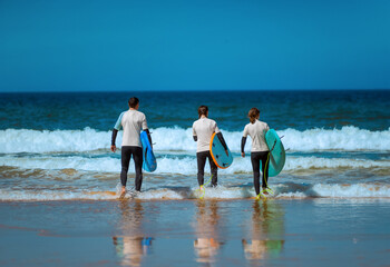 Surfers. Family of surfers learning to surf in the Atlantic ocean. First surfing lesson. Amateur...