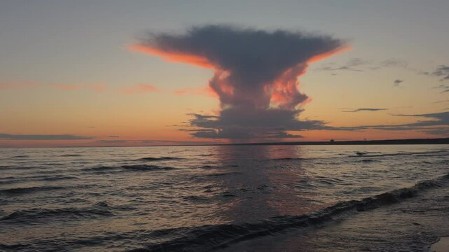 A strange huge cloud of smoke over the coast at sunset. There are clouds of nuclear mushroom over bay after an atomic explosion. picturesque landscape. Clouds of a strange shape are an anomaly