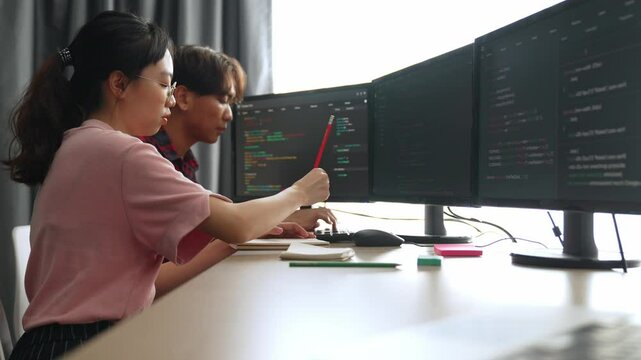 Slow motion back end software developer engineer for computer programming working together on debugging writing computing code, solving complex algorithms display on monitor in office. Burgeoning