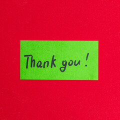 Green small note with the word thank you on a red background