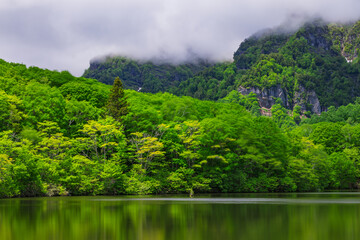日本　長野県長野市戸隠にある新緑の木々に囲まれた鏡池から眺める戸隠連峰