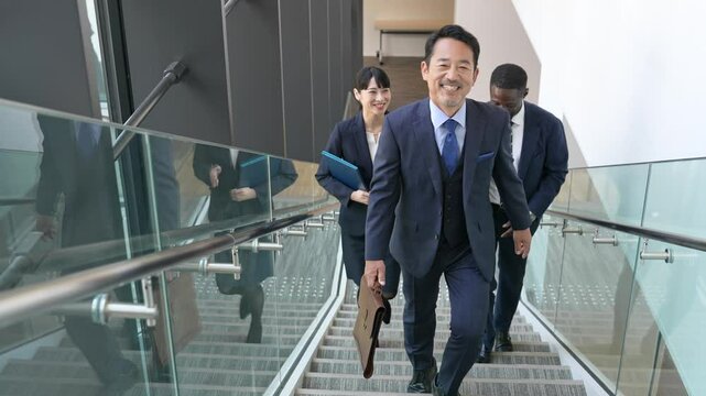 ビルの中を歩きながら会話する多国籍ビジネスパーソンのグループ