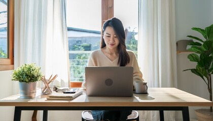 ノートパソコンを使って在宅勤務をしいている若いアジア人女性（Young Asian woman working from home using laptop） 