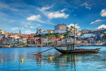 View of Porto city and Douro river with traditional boats with port wine barrels ship from famous tourist viewpoint Marginal de Gaia riverfront. Porto, Vila Nova de Gaia, Portugal