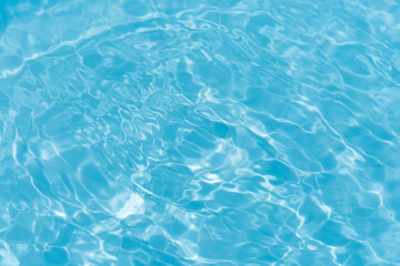 Blue water with ripples on the surface. Defocus blurred transparent blue colored clear calm water surface texture with splashes and bubbles. Water waves with shining pattern texture background.