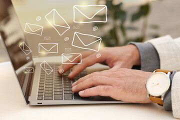 Man using laptop at table, closeup. E-mail address signs and envelopes over computer