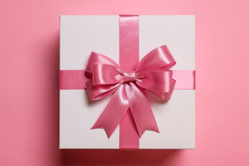 Gift box with bow on dusty pink background, top view