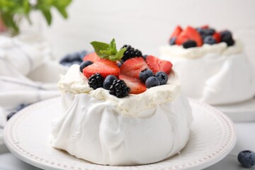 Pavlova cake (meringue dessert) with whipped cream, fresh berries and mint on table, closeup