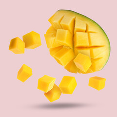 Sweet fresh mango cut in cubes falling on pink background