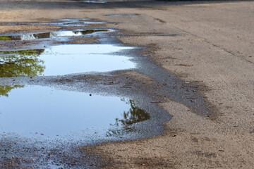 rain filled pot holes on road