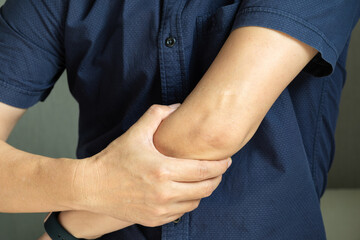 man has pain in his elbow and tendon muscles and he relieves the pain with a massage. Health and...