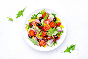 Vegan vegetable salad with olives, tomato, paprika, cucumber and onion, healthy mediterranean food. White background, top view