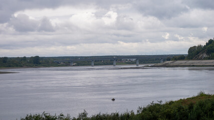 A bridge spans a river with a cloudy sky above