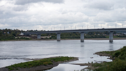 A bridge spans a river with a cloudy sky in the background