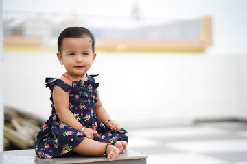 Sitting Pretty Baby in Blue, Adorable Baby in Floral Dress, Sitting Pretty Baby in Blue, Toddler in Floral Dress Sitting Calmly, Cute Baby Posing.