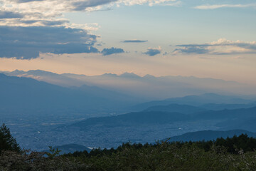 日本　長野県岡谷市と塩尻市の境にある高ボッチ山の高ボッチ高原　夕陽の光芒と山のグラデーションと夕焼け空