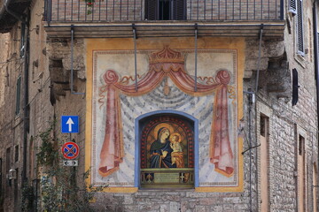 Obraz premium Assisi Building Facade with Tile Decoration Depicting a Madonna with Child in Umbria, Italy