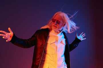 Stylish older man with long white hair and sunglasses posing confidently against a colorful gradient background His leather jacket adds a modern flair to the vibrant scene