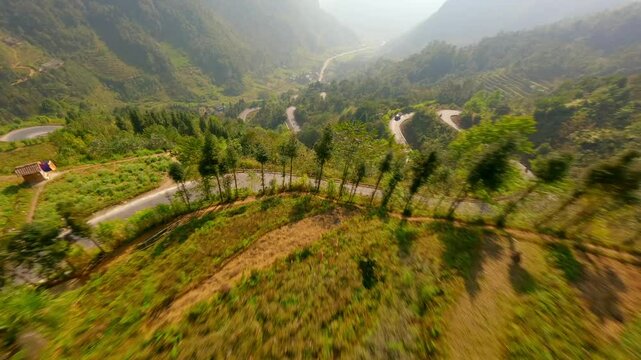 Cinematic FPV flight over rice terraces and winding road in the mountains on Ha Giang Loop in Vietnam