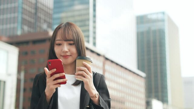 街でスマホを使う女性ビジネスパーソン