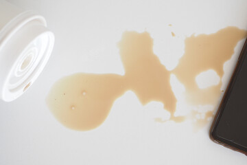 A drink was accidentally spilled on a desk with a laptop and glasses, creating a mess
