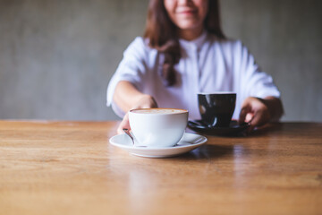 Closeup image of a young woman holding and serving two cups of hot coffee