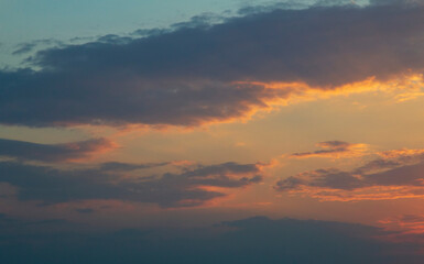 dark blue in places white-gray dense clouds in the lower layers are colored at the edges by the rays of the sun in pale orange shades