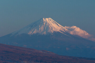 冬のビーナスラインから遠望する夕陽に染まる冠雪した富士山