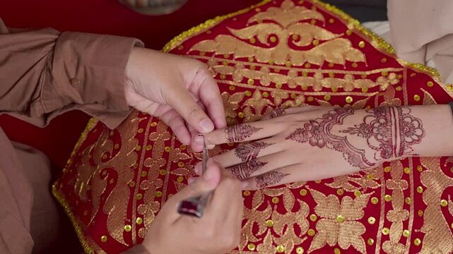 The process of painting henna on the bride's hands. There are many different names for henna tattoo across the globe, such as mehndi, inai, hina, camphire, and hena