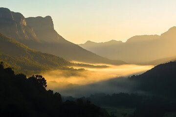 Majestic mountain range bathed in the golden light of sunrise, with a mist-covered valley below