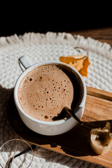 Mocha coffee in a white flatlay cup, autumn coffee, morning routine, coffee in the sunlight, wax candles, cozy breakfast, coffee with foam, mocha on a wooden table and a round napkin, autumn leaves