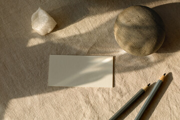 Overhead view of a blank business card on a table with pencils and assorted ceramics.