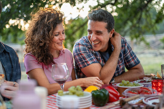 Happy middle-aged couple enjoying outdoor dinner, romantic picnic with fresh food and wine - Powered by Adobe