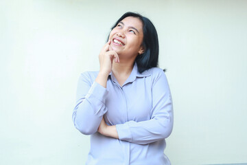 Fototapeta premium excited asian young business woman smiling with hand ond chin and folded arm looking up thinking idea solution and imagining dream, dressed in formal suit employee, isolated over white background