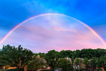 Spectacular rainbow above a New Jersey suburban community with wooden houses.