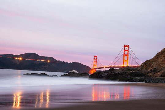 Golden Gate Bridge reflecting in calm waters at twilight, soft waves. - Powered by Adobe