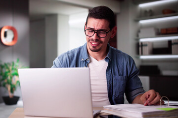 Young Man Suffering From Headache With Invoice
