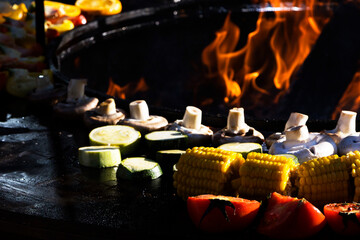 A person wearing black gloves is preparing food on a grill outdoors