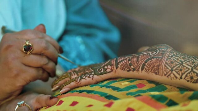 Artist applying henna tattoo on women hands. Mehndi is traditional decorative art. Close-up