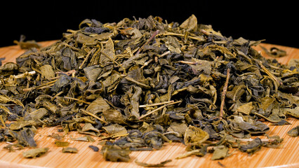 Close-up image of dried green tea leaves on black background.