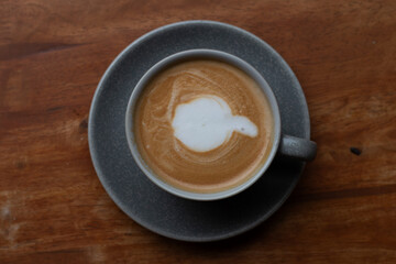 A cup of coffee, hot Latte, lace on the wooden table with a natural background.