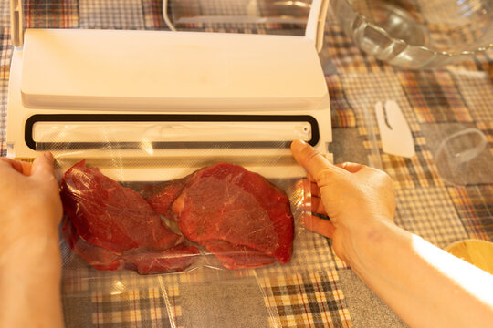Female hands vacuum sealing beef in a plastic bag and getting it ready for the freezer