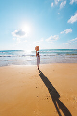 Obraz premium Happy woman enjoying the sun and sea. A carefree girl walks along the beach on a sunny day.