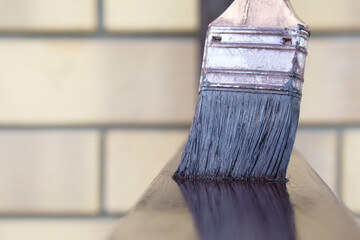 paint brush in brown paint close-up painting metal structure