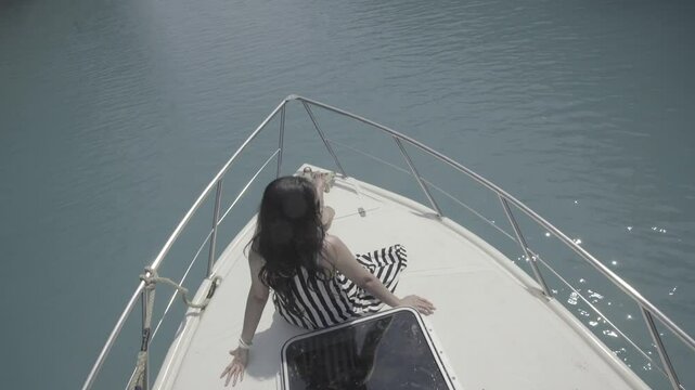 Beautiful girl leaning on yacht, enjoying a peaceful ocean view. S-log format.
