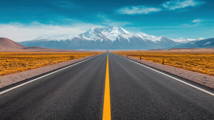 Fototapeta premium A straight road leading under a snow-capped mountain.